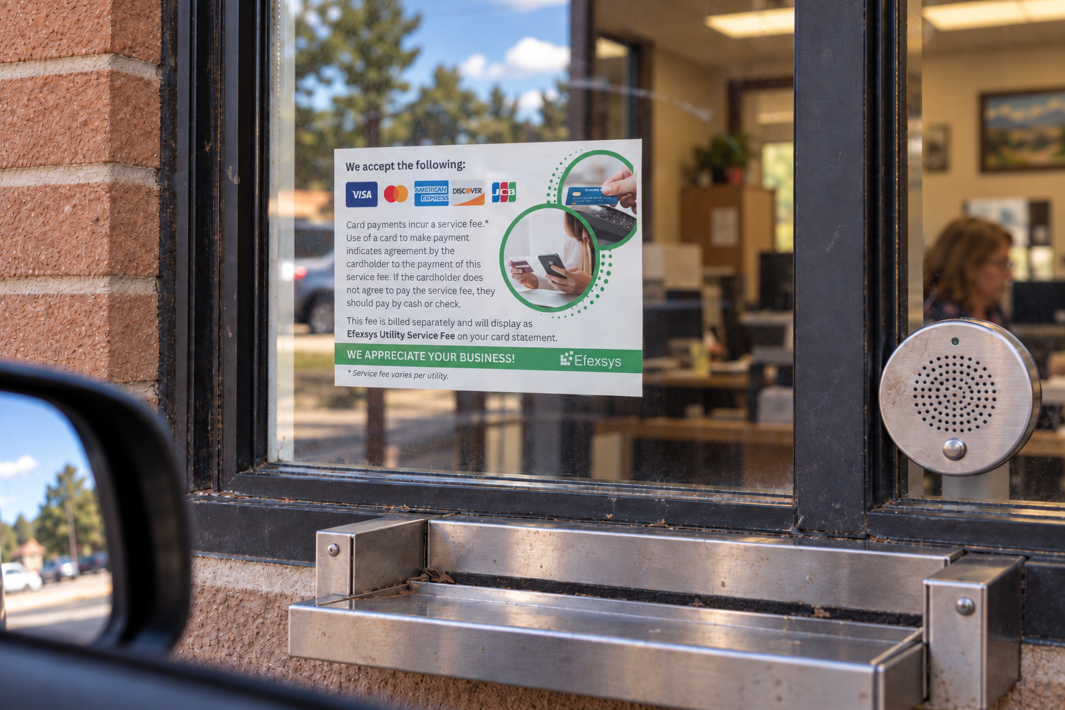 Efexsys card payment notice posted behind the glass of a utility drive-up payment window.